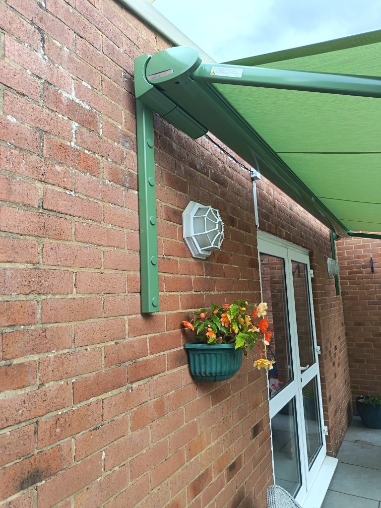 Side detail of green Weinor Cassita cassette and bracket on brickwork in Bearsted