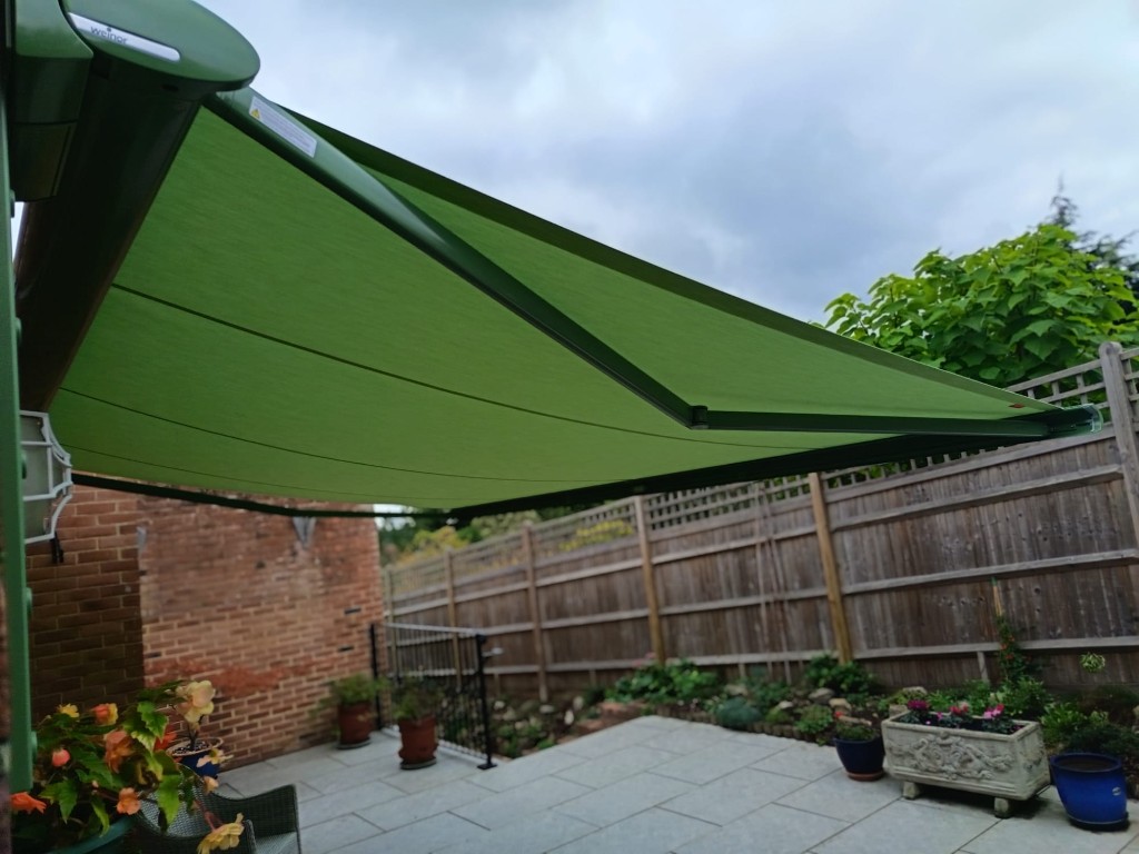 Weinor Cassita green awning fully projected over stone patio and fence in Bearsted, Kent