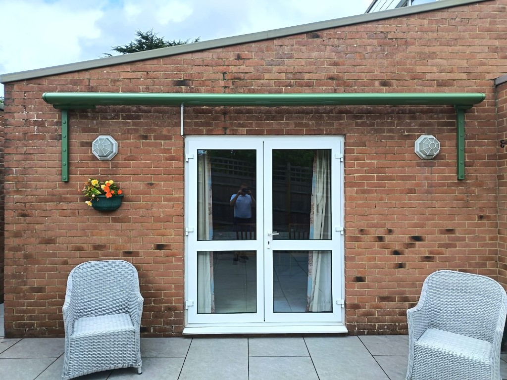 Green Weinor Cassita cassette retracted above white French doors on a brick house in Bearsted