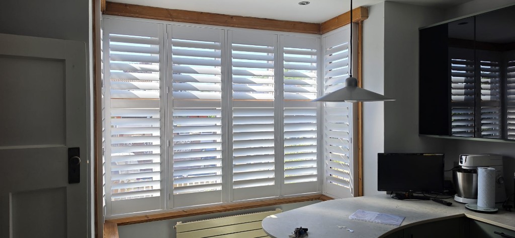 Wide-angle view of full-height hardwood shutters with 89mm louvres in a Maidstone kitchen, Kent