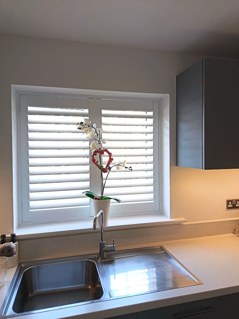Polylite pure white shutters with 76mm louvres above a kitchen sink in Snodland, Kent