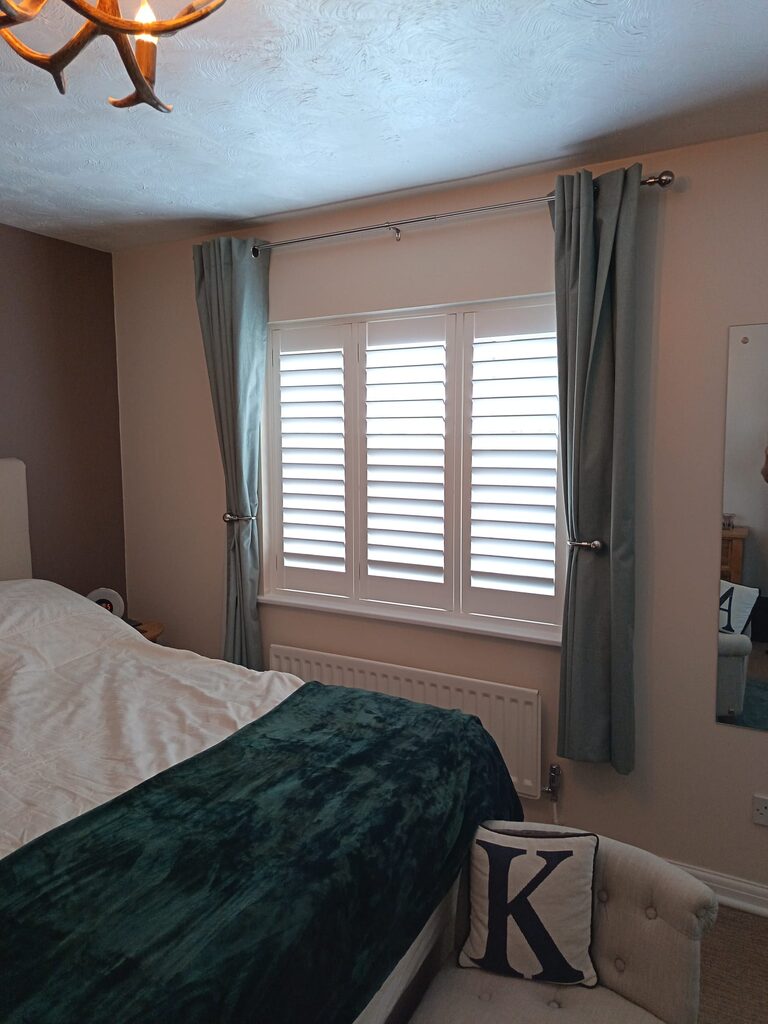 Super White hardwood shutters fitted behind curtains in a Tovil bedroom