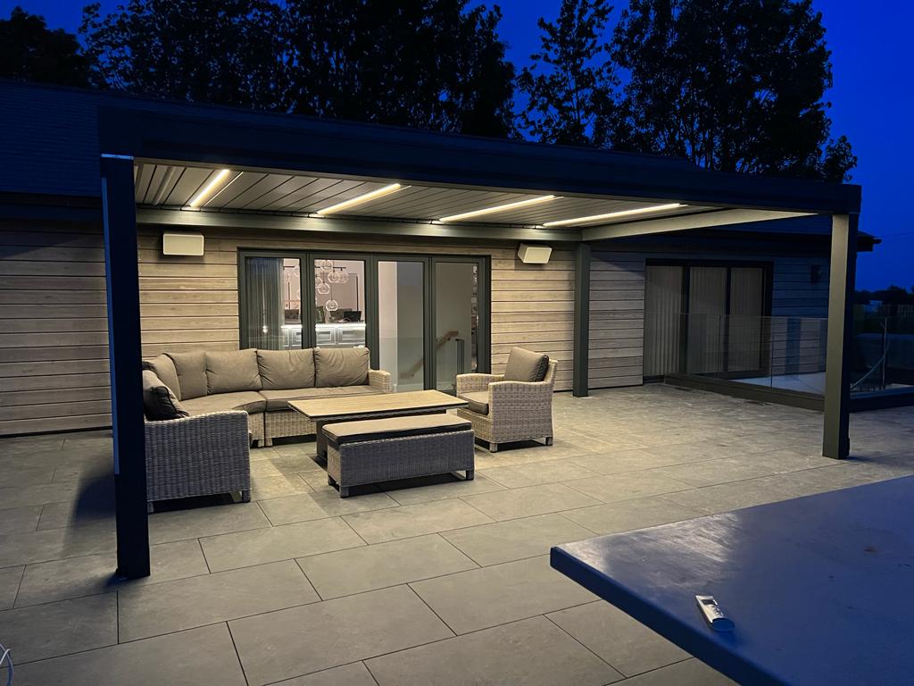 Aluminium pergola with integrated lighting over an evening patio seating area in Kent